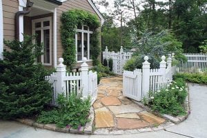 Curb appeal, a white fence, paved walkway, evergreen and flowers