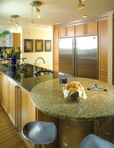 Kitchen island topped with Black Galaxy granite and round inset breakfast table of Giallo Florence granite