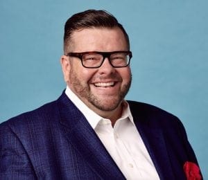 Photo of Designer Kerry Howard. Man in sport coat, glasses, and dark hair and beard.