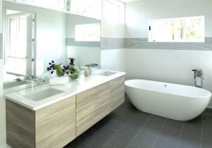 Sleek modern bathroom with white counter tops and large white soaker tub