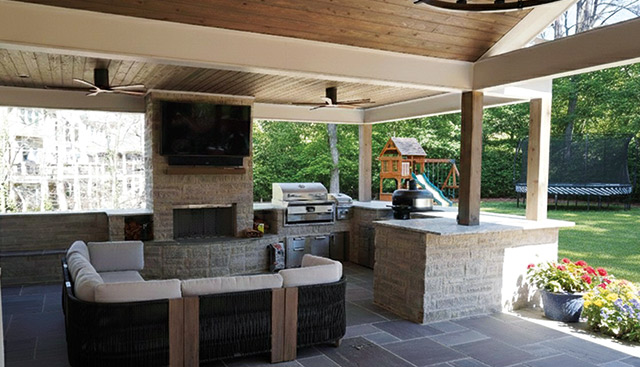 Outdoor kitchen with a grill, a big green egg, fireplace and bar